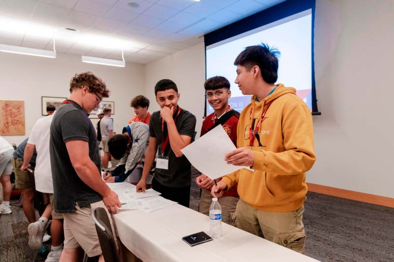 a group of young men standing at a table with papers