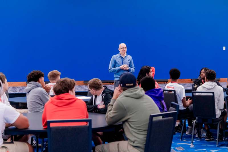 a man standing in front of a group of people sitting around a table