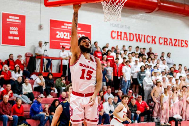 a basketball player in a red uniform dunking a basketball hoop