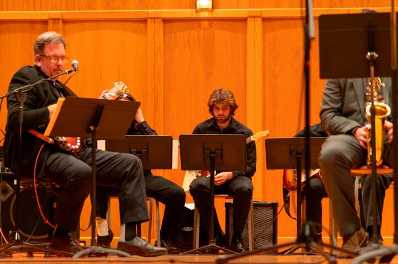 a group of people sitting on chairs playing instruments