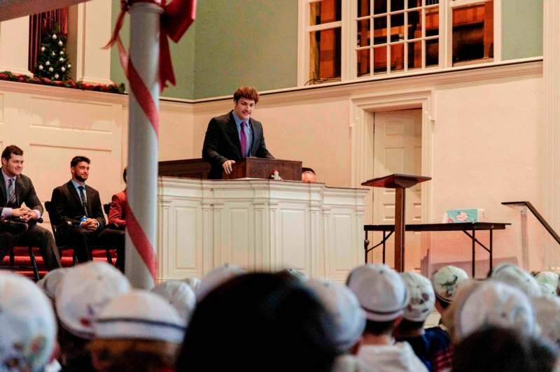 a man standing at a podium with a crowd watching