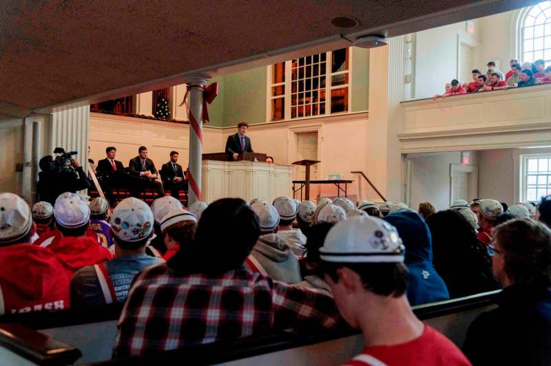 a man standing at a podium with a crowd of people in the background