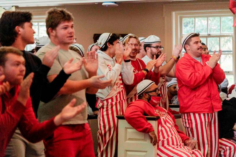 a group of people in striped aprons clapping