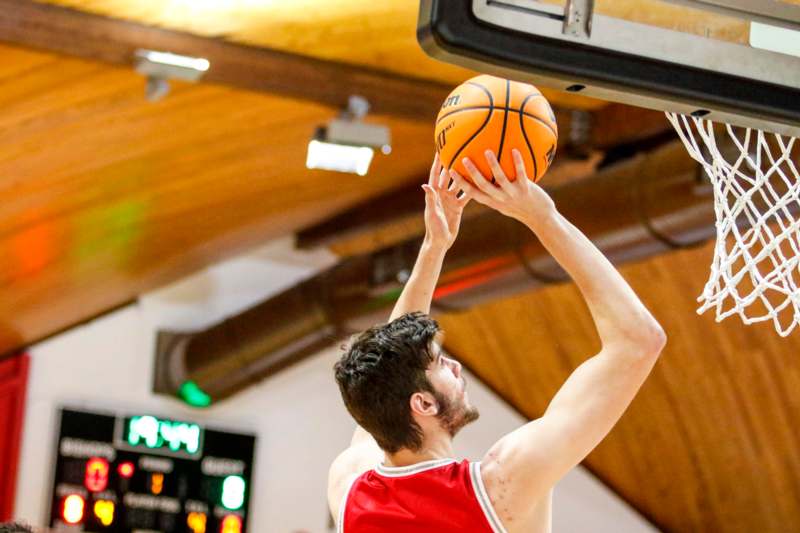 a man in a red shirt and shorts playing basketball