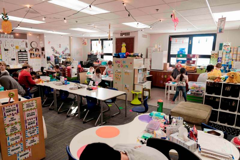 a room with many tables and chairs and a group of kids