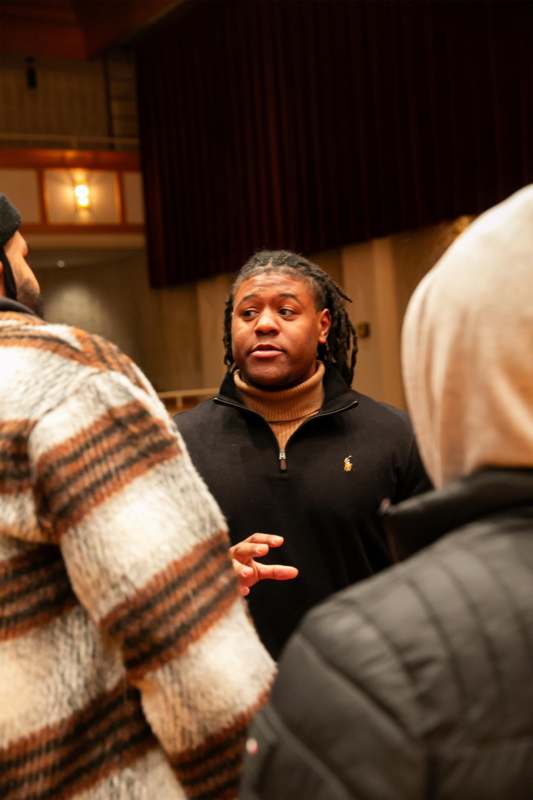 a man in a black sweater talking to a group of men