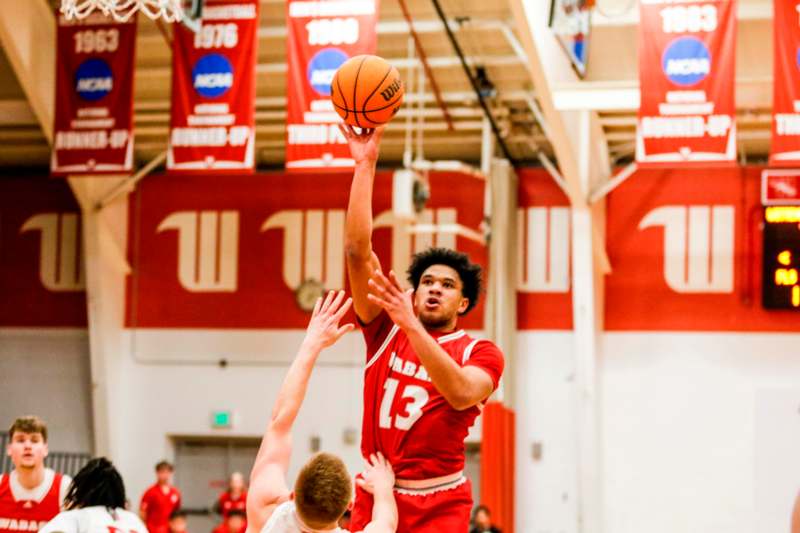 a basketball player in red uniform jumping to shoot a basketball