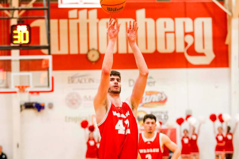 a man in a red uniform jumping to shoot a basketball