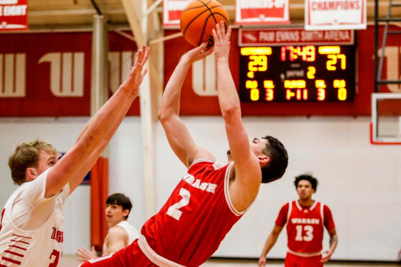 a basketball player in a red uniform jumping to shoot a basketball