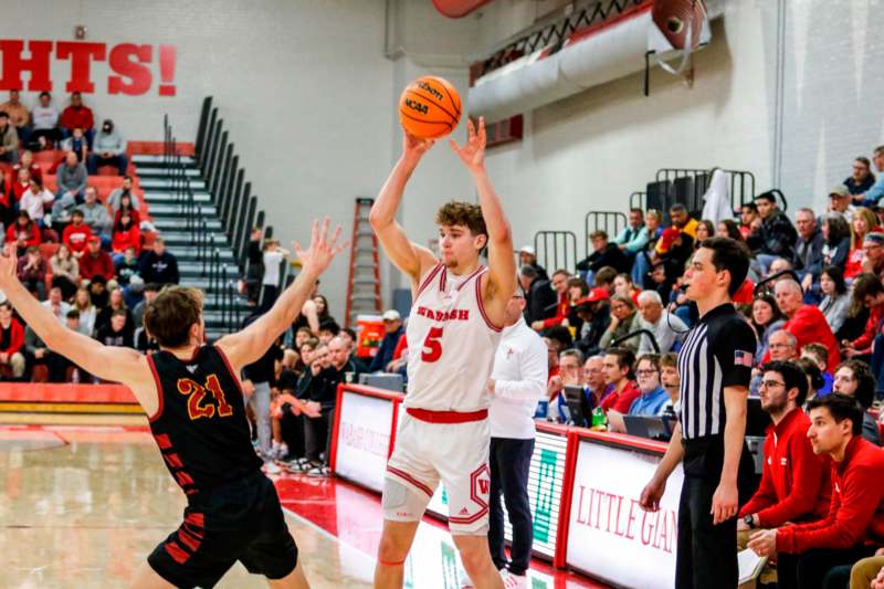 a basketball player in a red uniform with a ball in the air