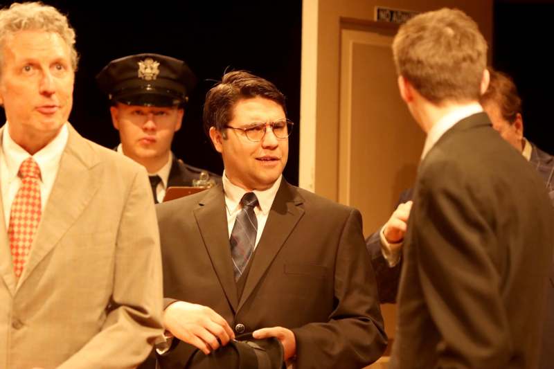 a man in a suit and tie talking to a group of men