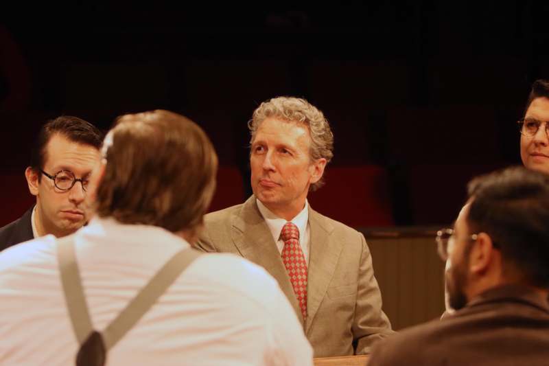 a man in a suit and tie talking to a group of men