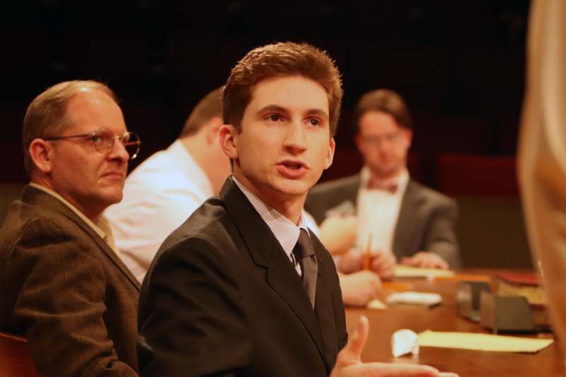 a man in a suit speaking to a group of men