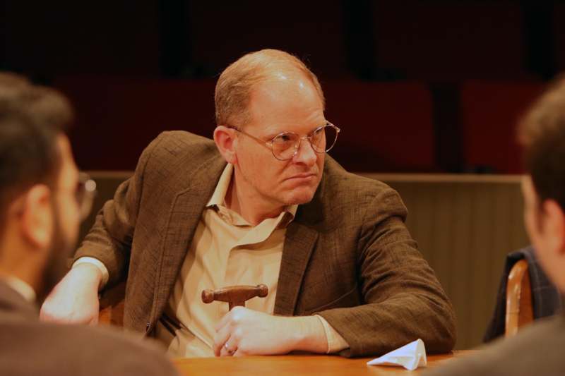 a man in a suit sitting at a table with a hammer