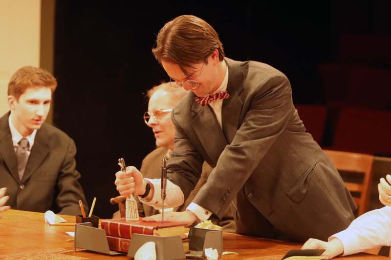 a man in a suit and bow tie holding a book