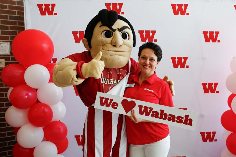 a woman standing next to a person wearing a mascot