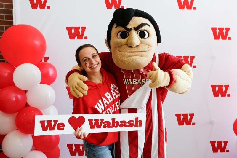 a woman holding a sign with a mascot