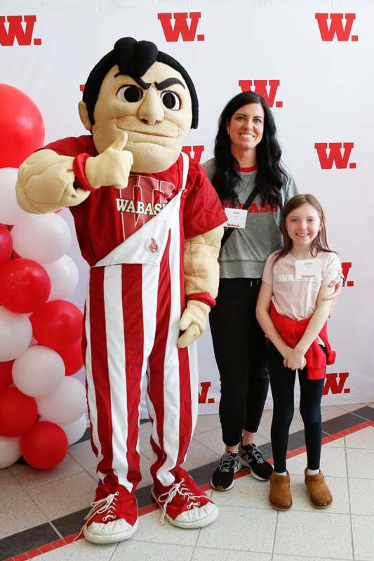 a woman and a girl posing with a mascot