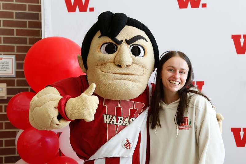 a woman smiling next to a mascot