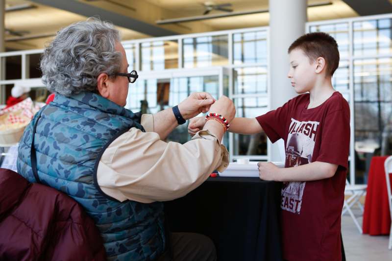 a man putting on a bracelet on a boy's wrist