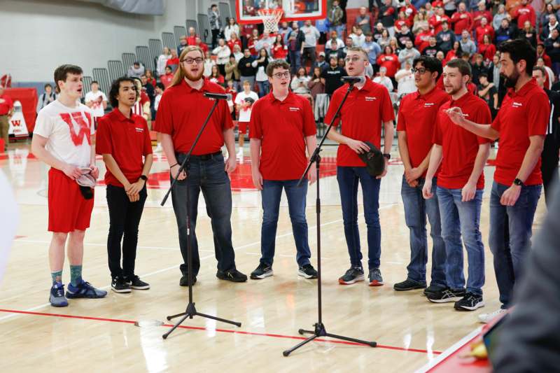 a group of people singing in a basketball court