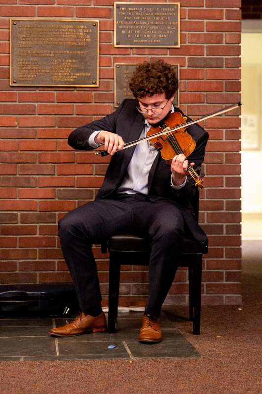 a man sitting in a chair playing a violin