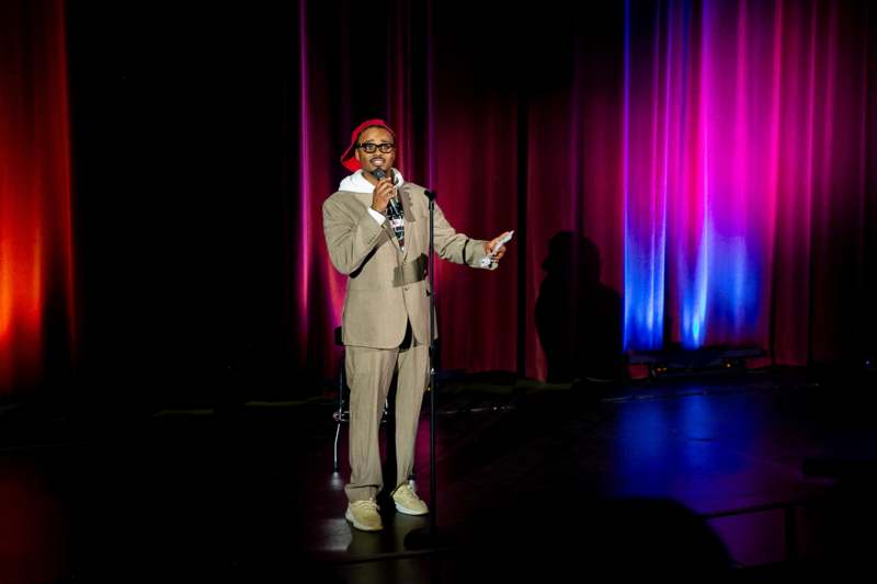 a man wearing a suit and hat holding a microphone