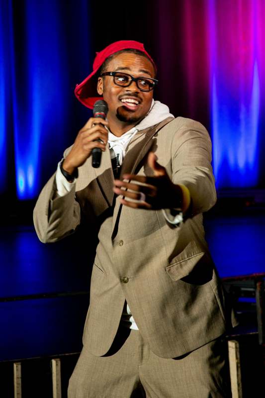 a man wearing a red hat and suit jacket holding a microphone