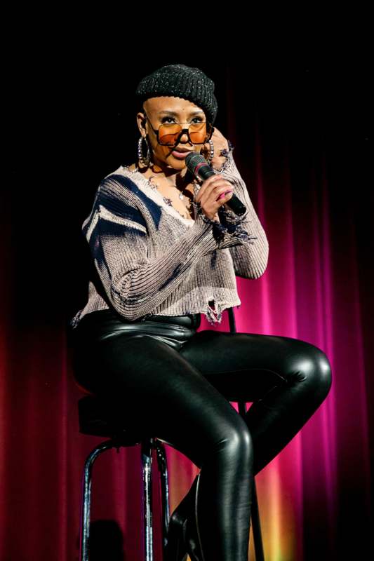 a woman sitting on a stool holding a microphone