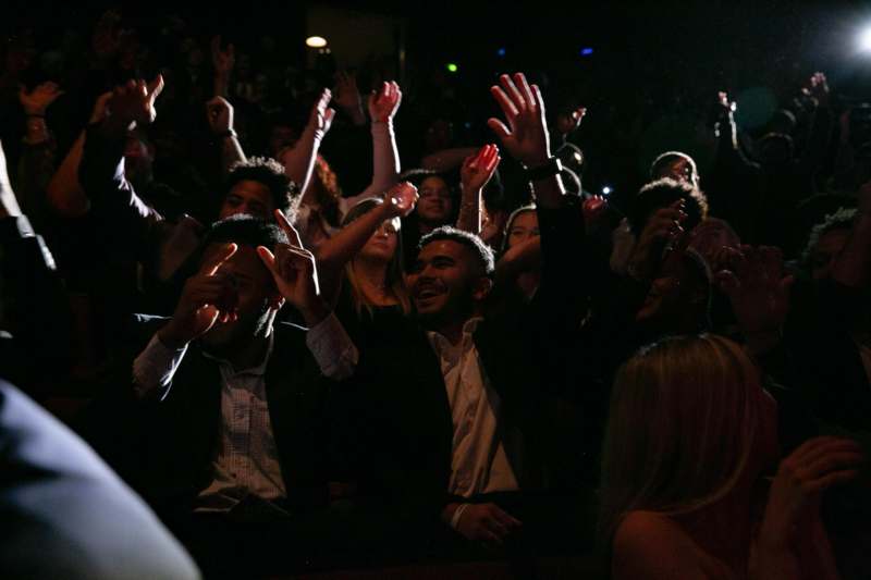 a group of people in a dark room with their hands up